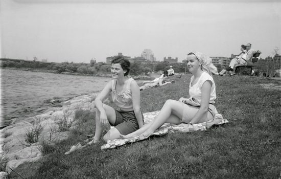 women sitting on grass next to water